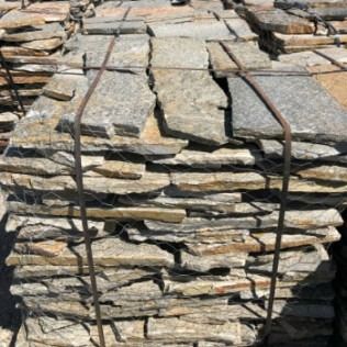 Stack of irregularly shaped natural stone pavers secured with metal straps.