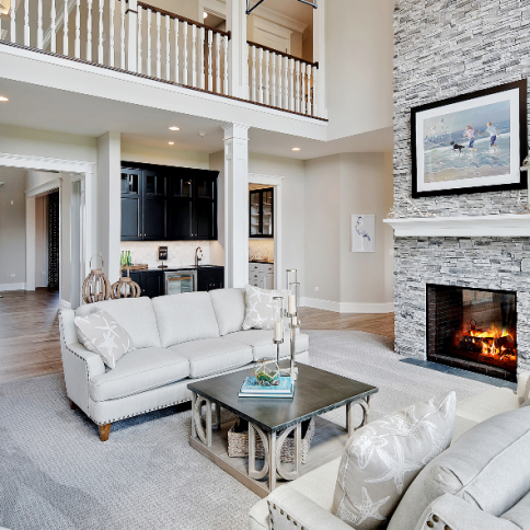Living room with fireplace, white sofa, stone wall, and balcony.