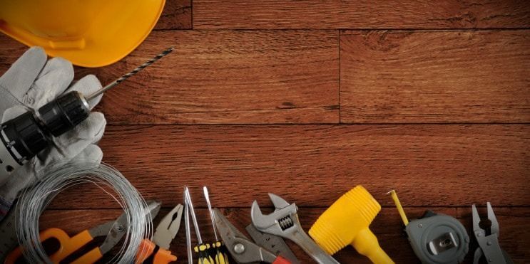 Construction tools on wood background. Drill, gloves, tape measure, hammer, pliers, and wire.