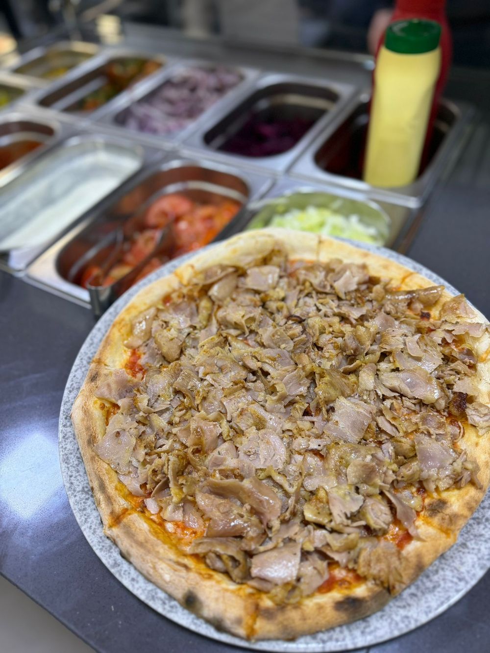Una pizza condita con peperoni, olive nere e cipolle rosse tagliate a fettine sottili, su una base leggera e dorata.