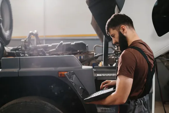 Mechanic checking a tablet beside a lifted vehicle in a garage