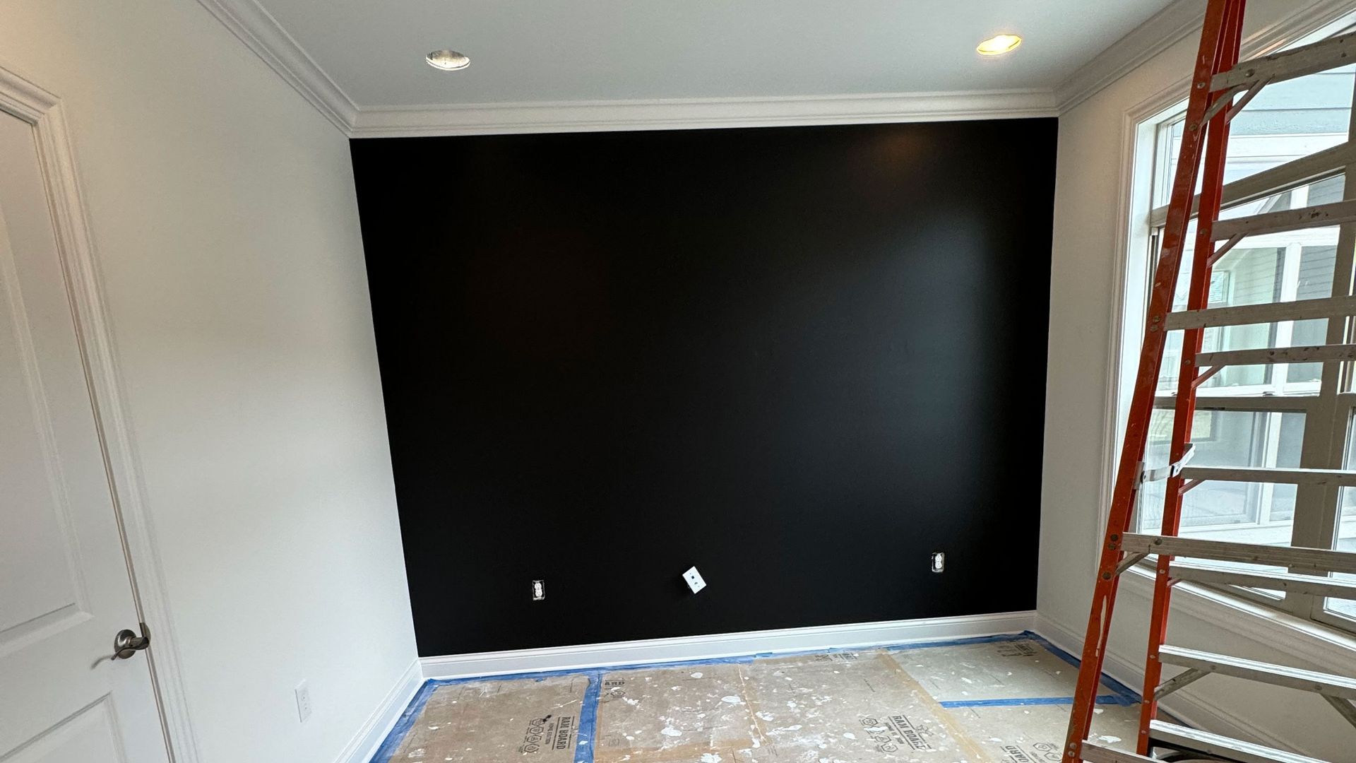 A room with a black wall and a ladder in it.