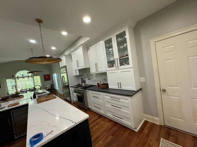 A kitchen with white cabinets , black counter tops , and stainless steel appliances. A kitchen with white cabinets , black counter tops , and stainless steel appliances.
