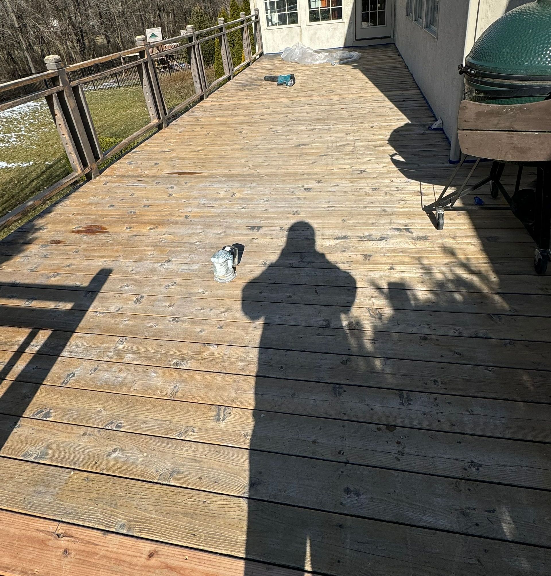 A shadow of a person is cast on a wooden deck.