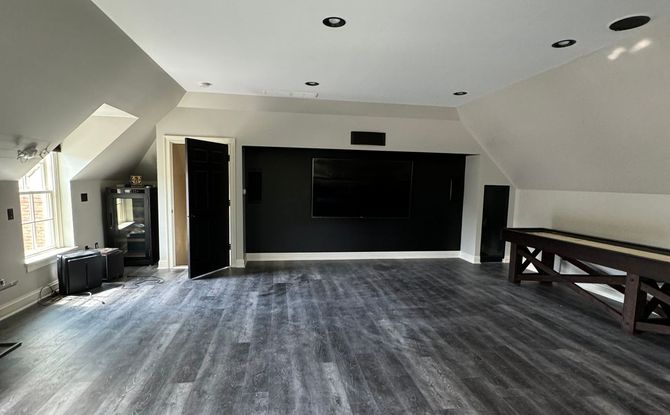 A large empty room with a wooden table and a black wall. A large empty room with a wooden table and a black wall.