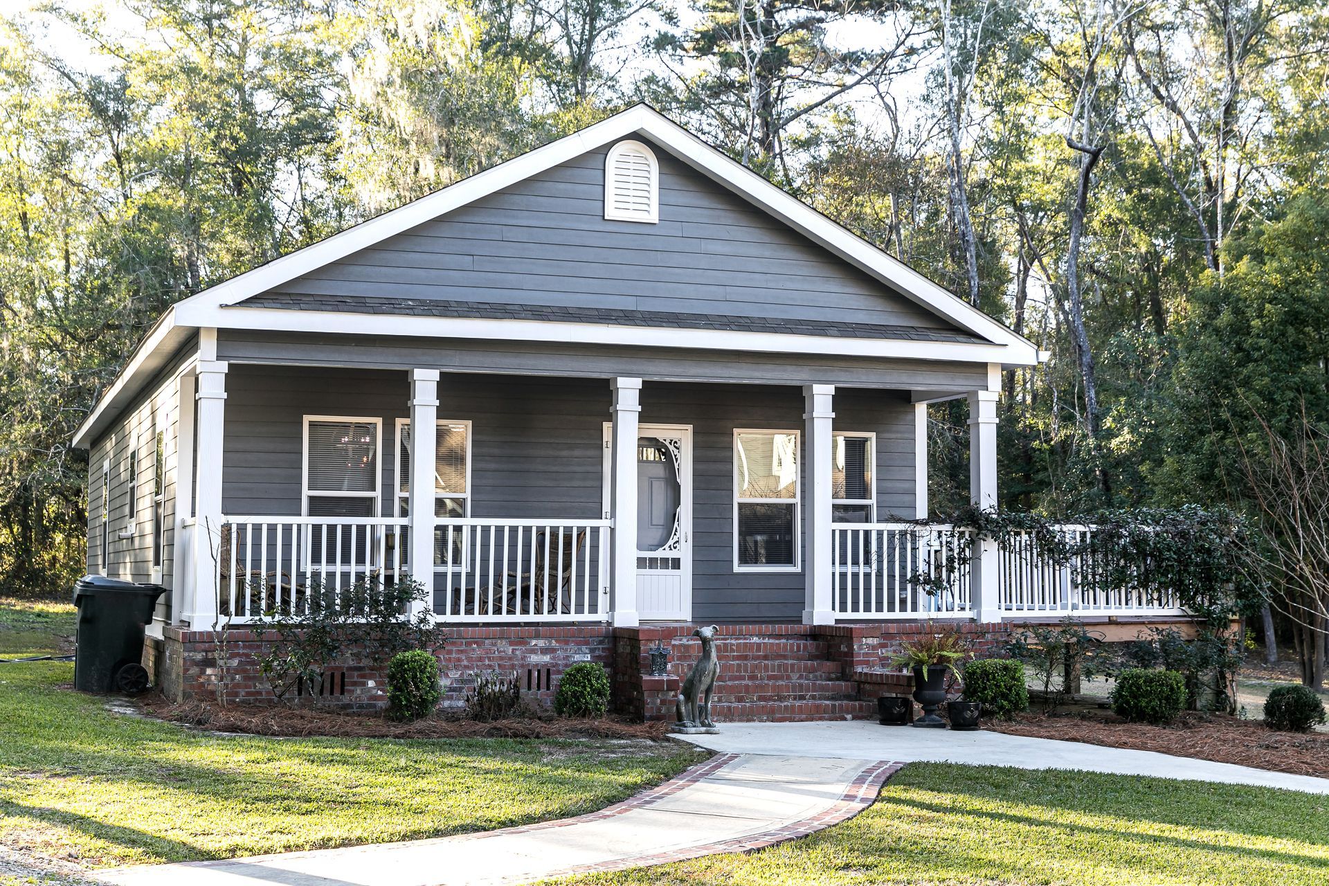 Single-family home with a covered front porch, landscaped yard, and wooded surroundings.