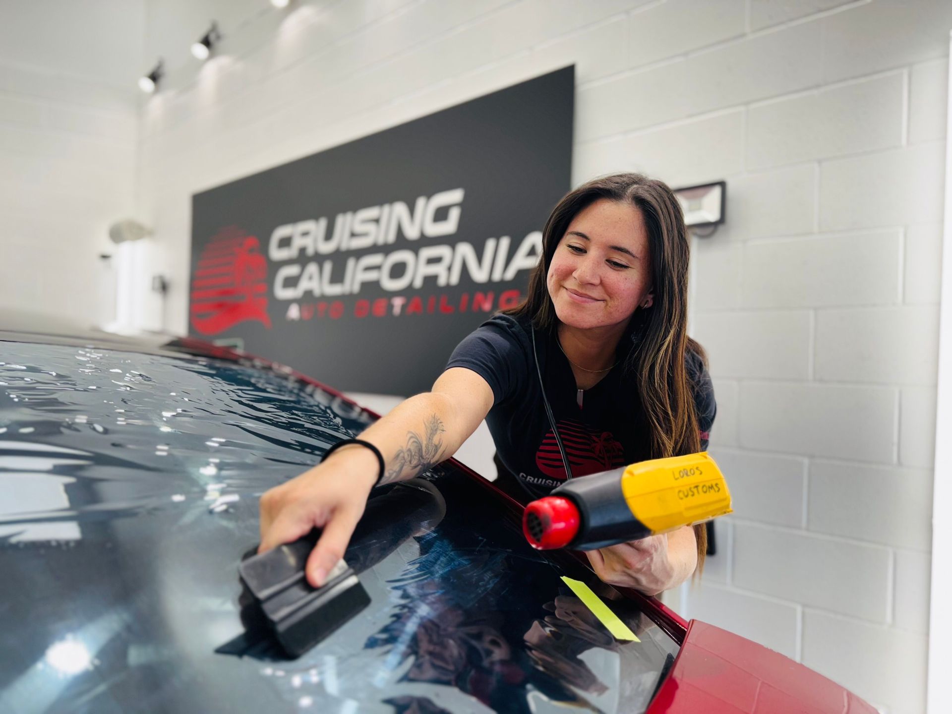 A woman is cleaning the windshield of a car.