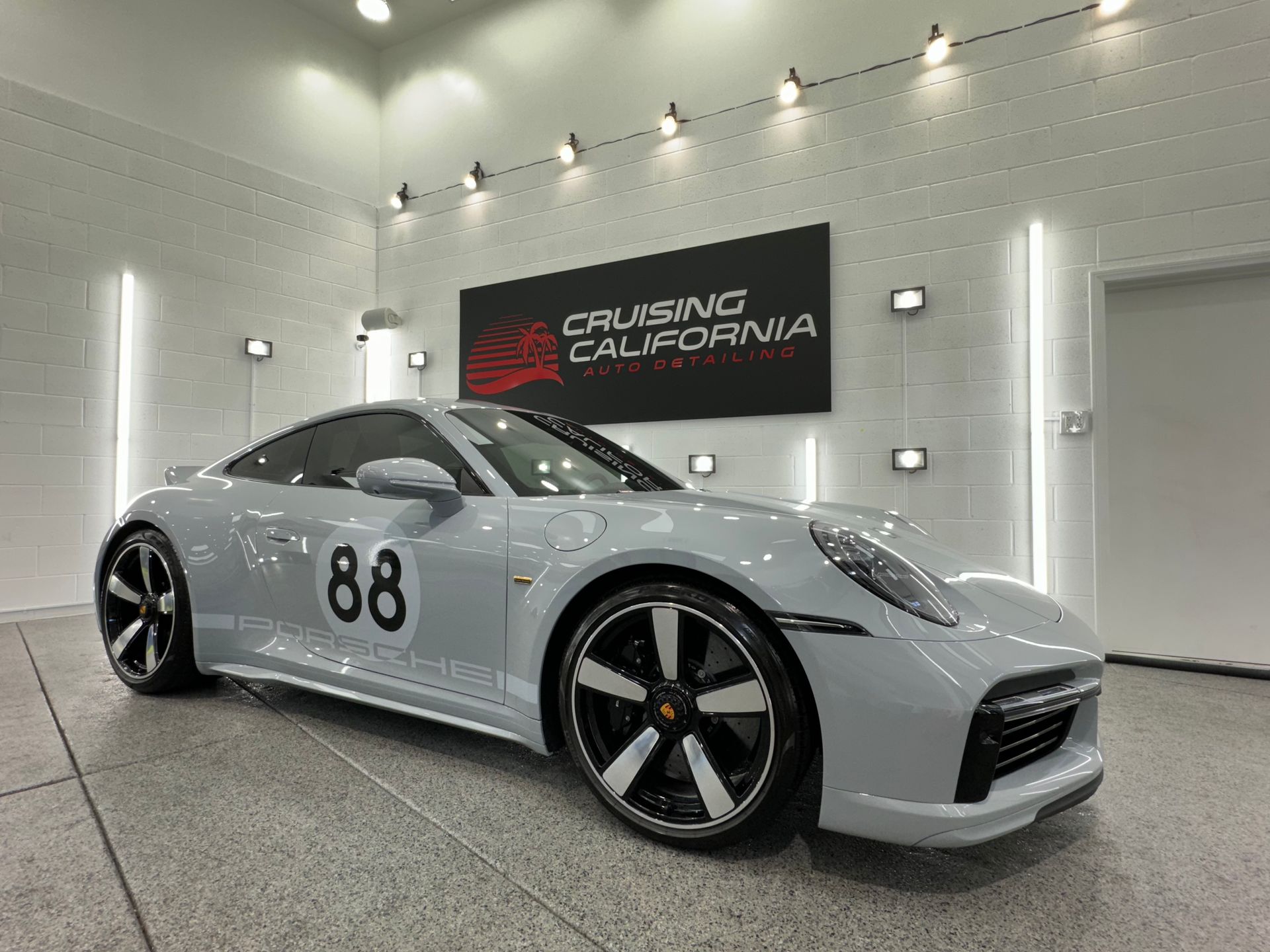 A white porsche 911 is parked in a garage.