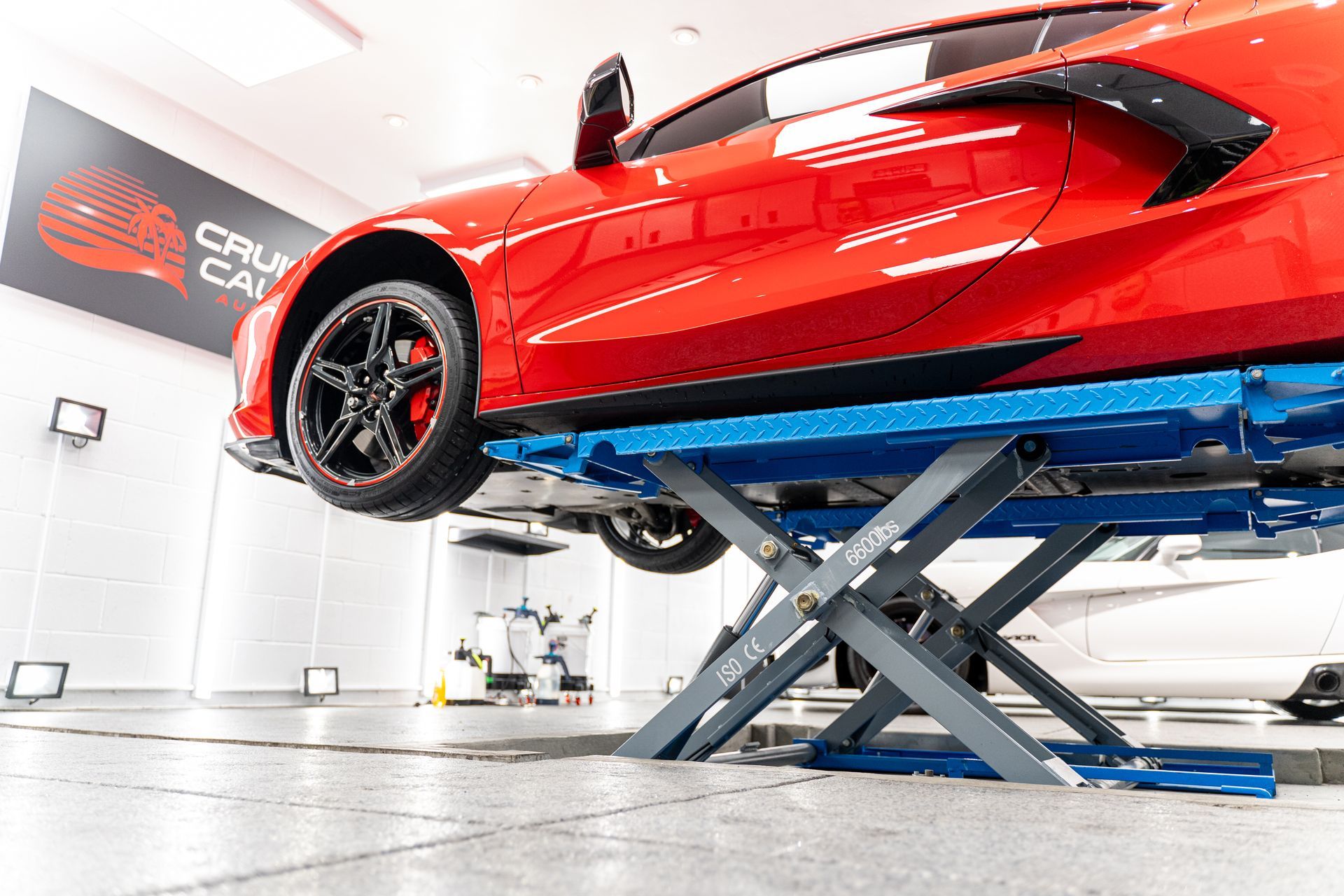 A red sports car is sitting on a lift in a garage.