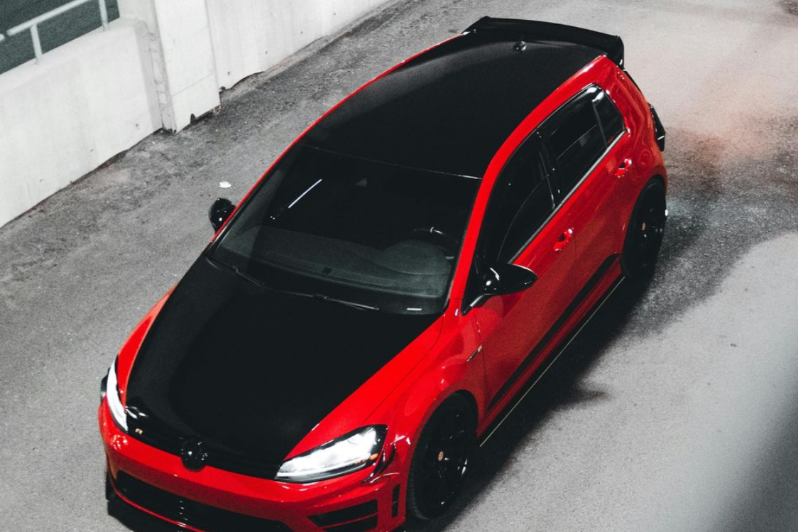 Red hatchback car parked in an alley, viewed from above.