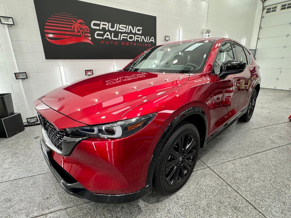 A red car is parked in a garage next to a sign that says cruising california.