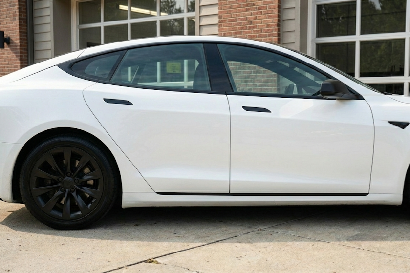 White sedan parked in front of a building with large windows