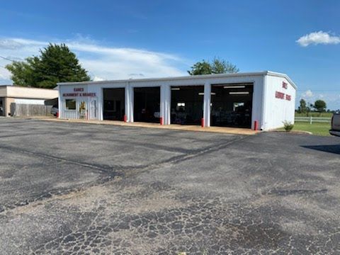 A white auto repair shop with four bays. A sign reads 