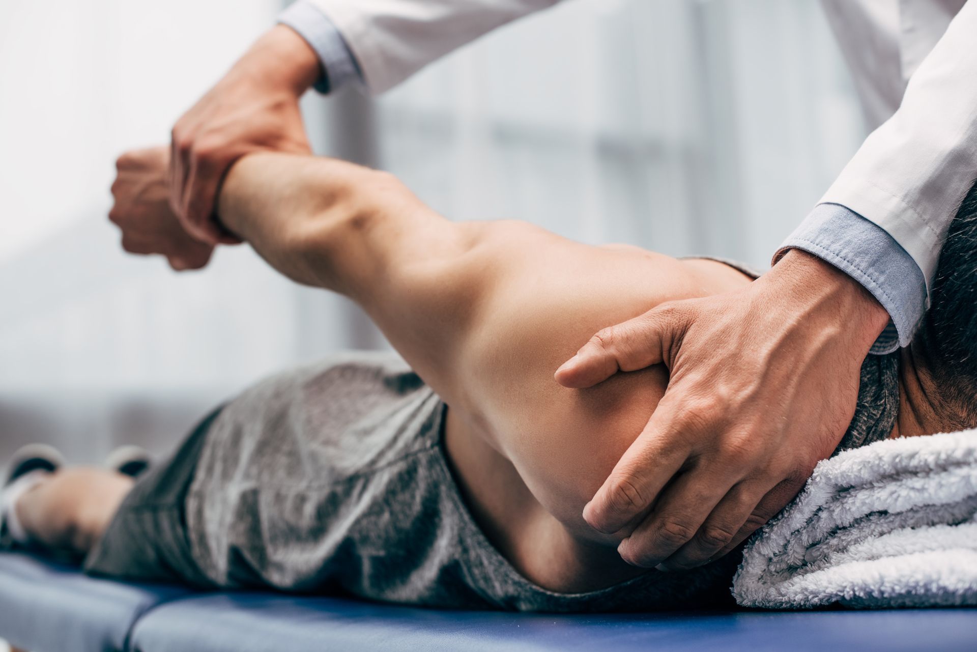 Person receiving shoulder manipulation by a doctor in a medical setting.