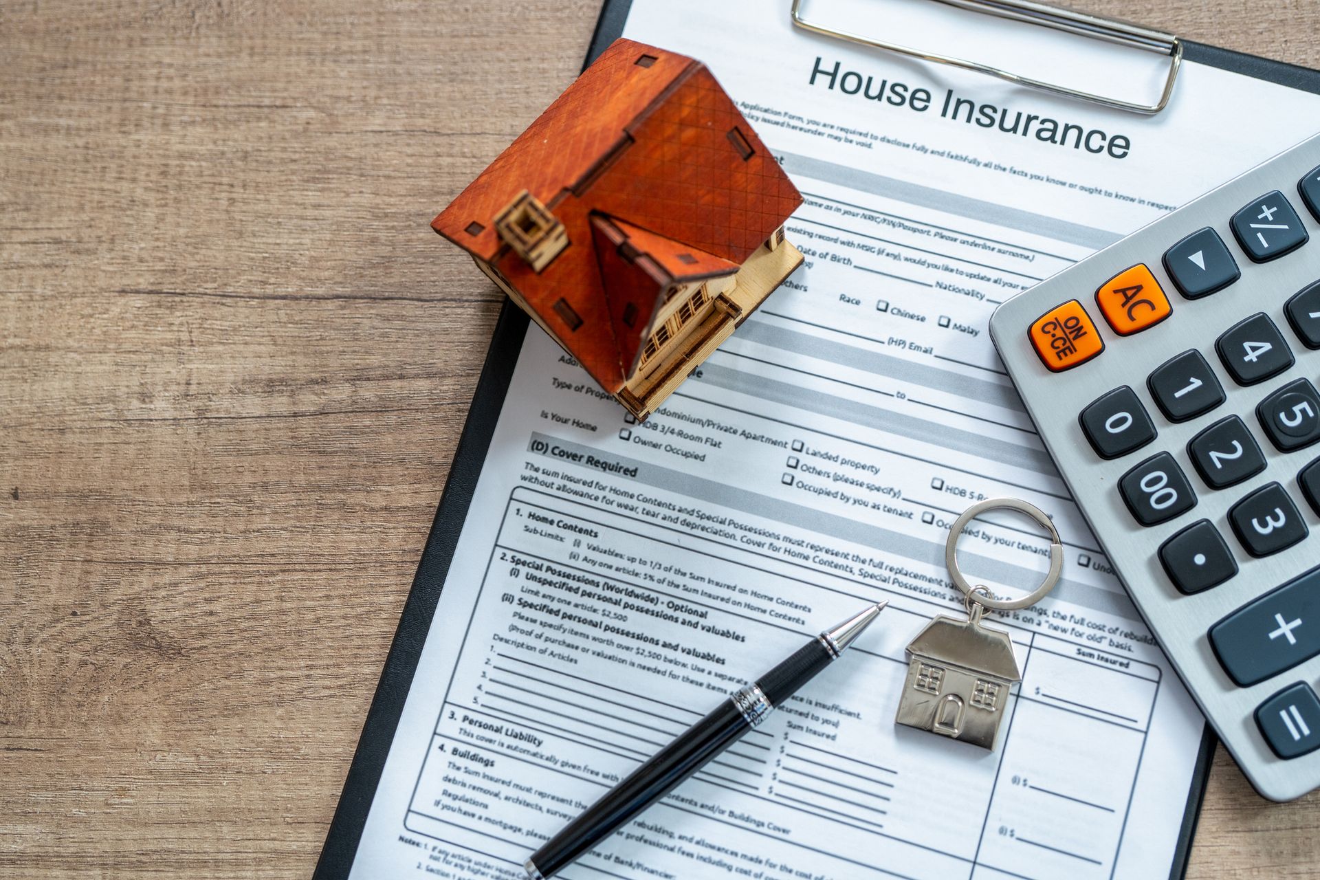 Mobile home insurance policy form with toy house, calculator, and pen on wooden desk.
