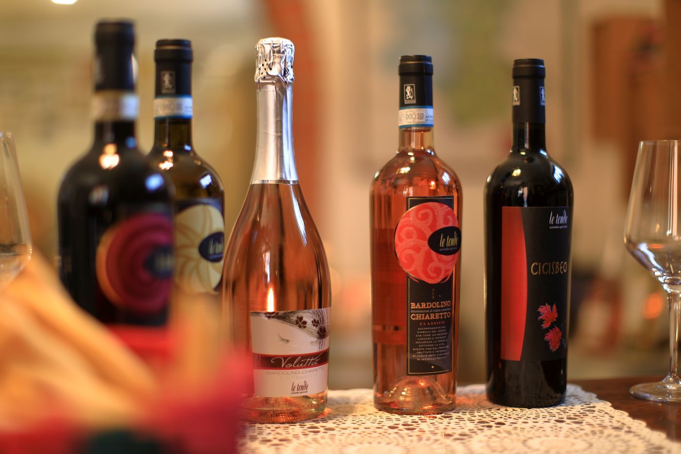 Diverse bottiglie di vino su un tavolo, con un calice in primo piano.