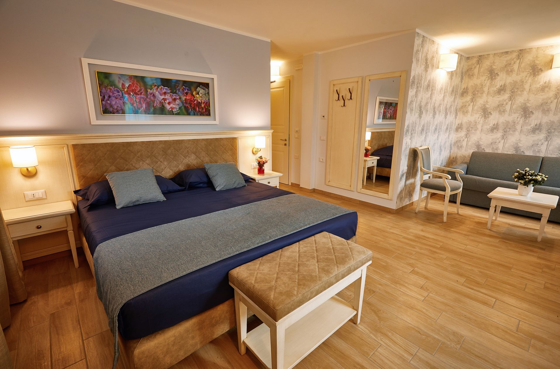 Gemütliches Schlafzimmer mit großem Bett, blauer Bettwäsche, Holzboden und warmen Nachttischlampen