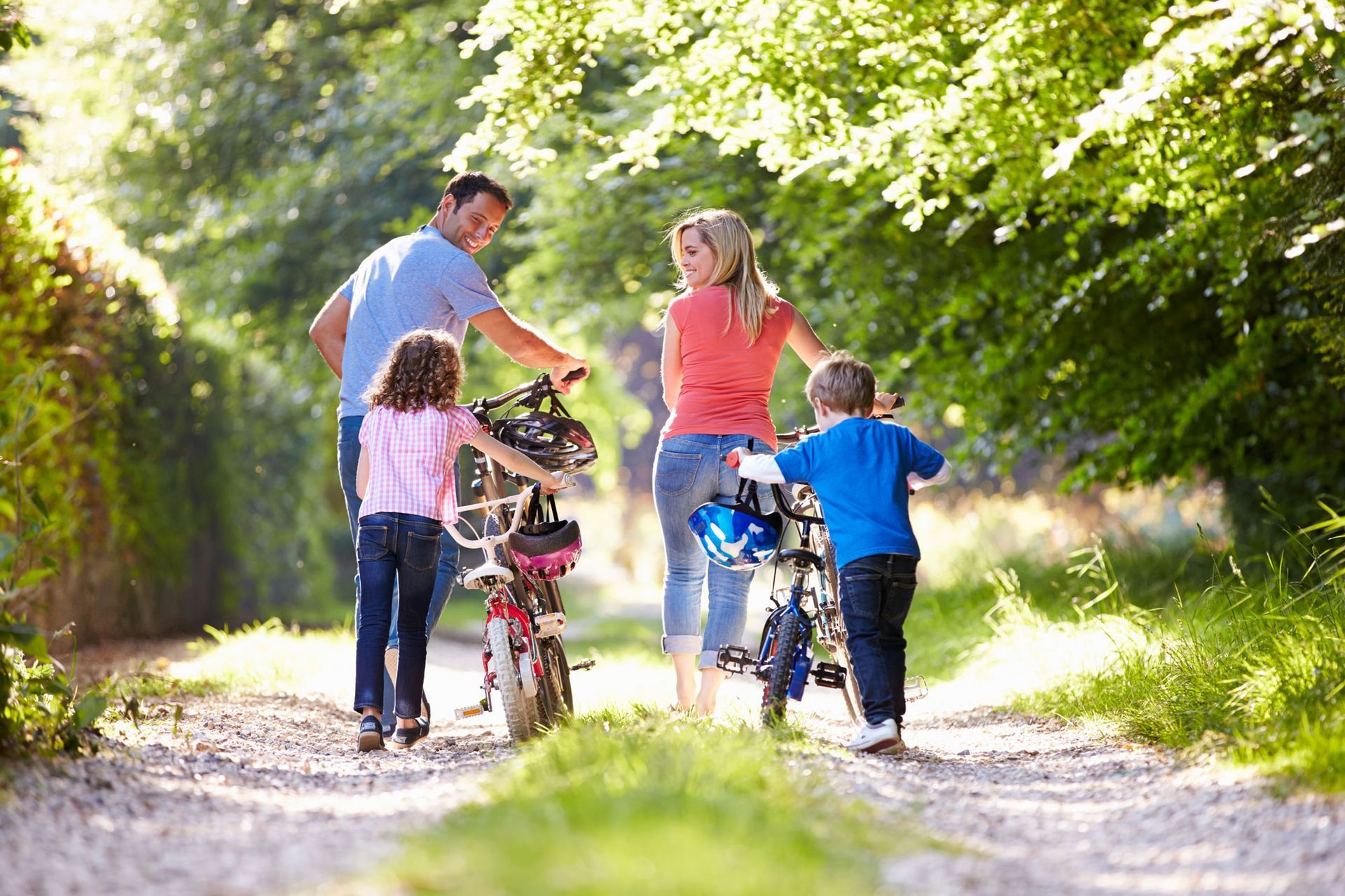Family with children and bicycles on a sunny tree-lined path