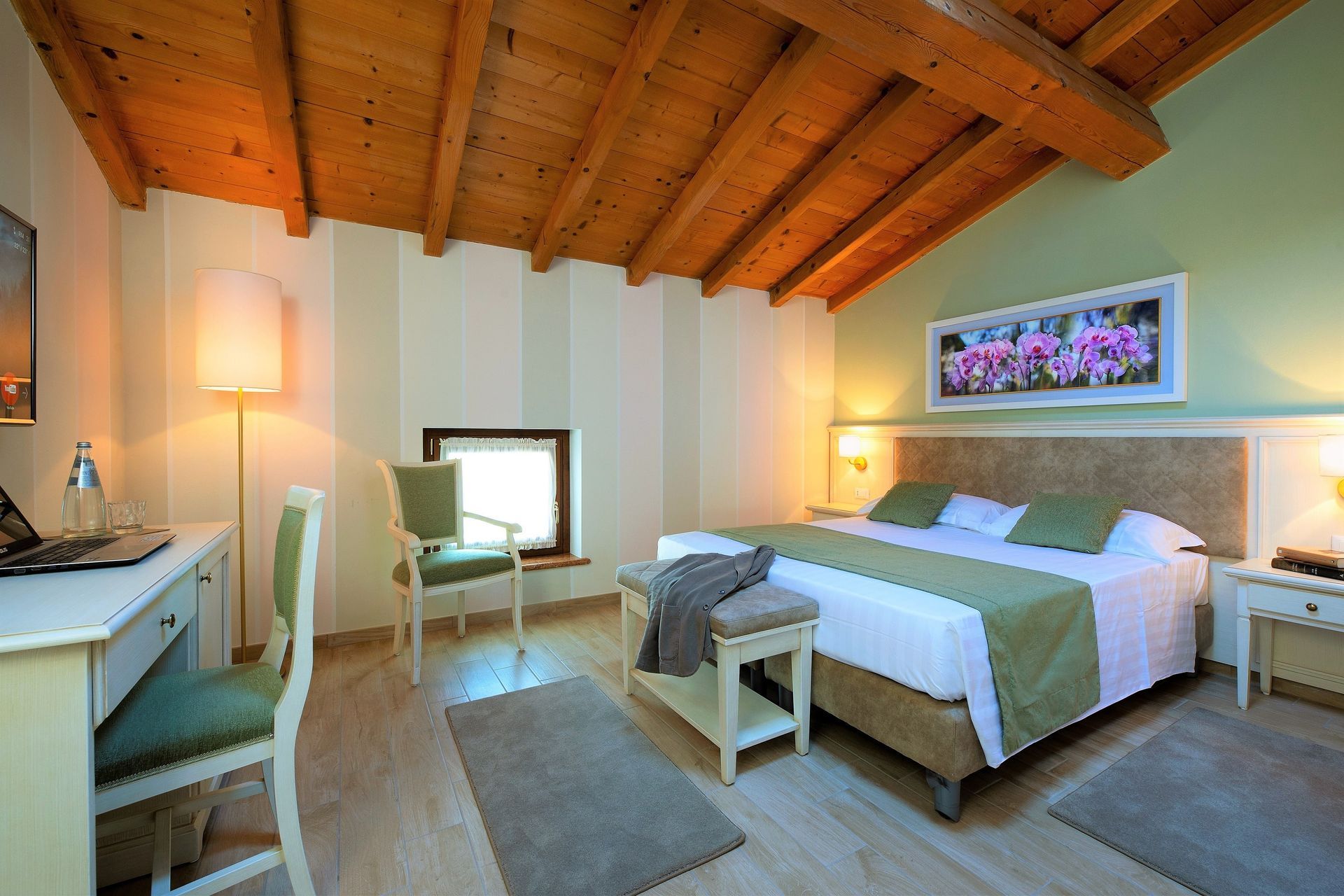 Helles Schlafzimmer mit Holzdecke, Bett, Schreibtisch, Lampe und kleiner Fensternische