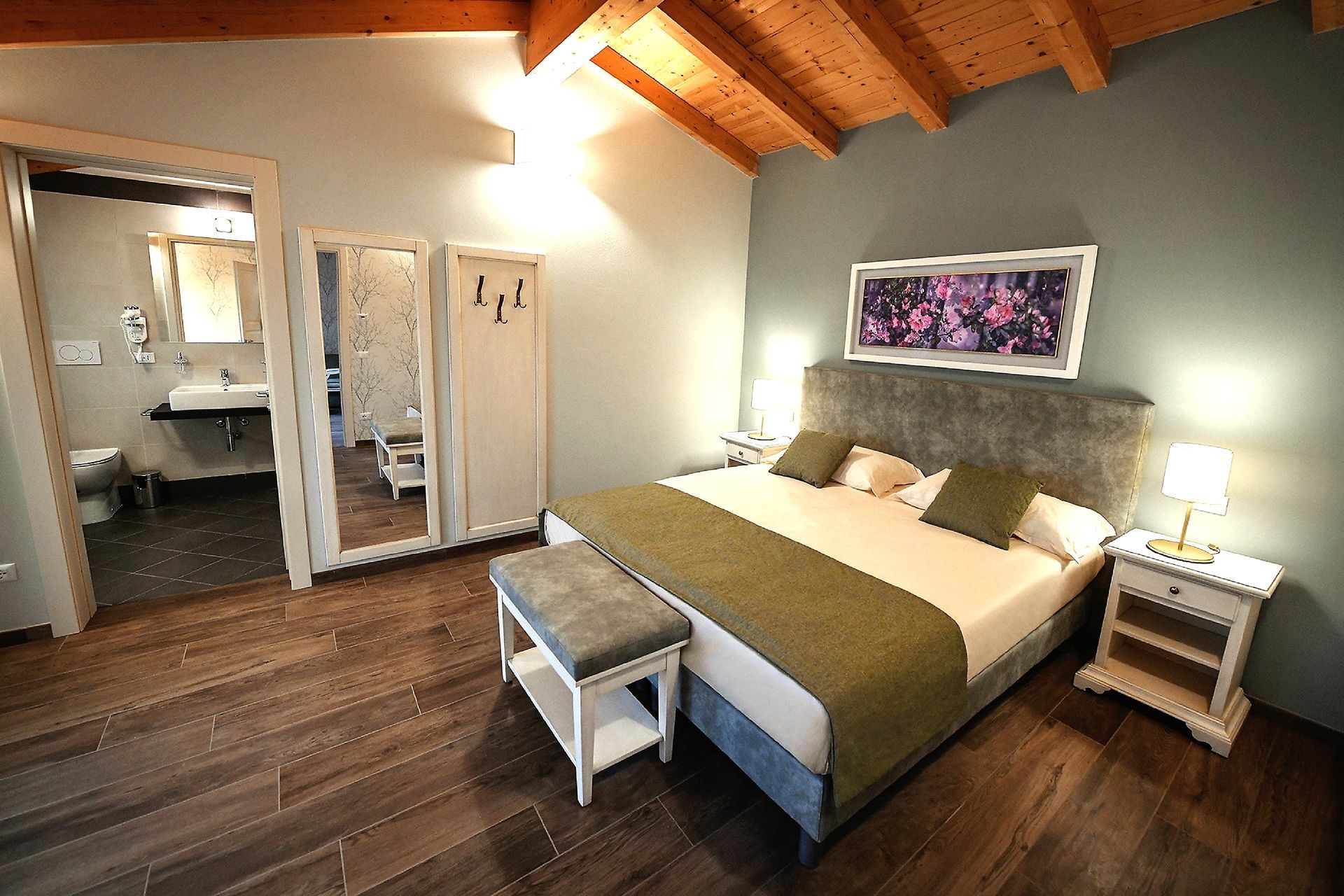 Gemütliches Schlafzimmer mit Kingsize-Bett, Holzboden, Gewölbedecke und Badezimmertür links.