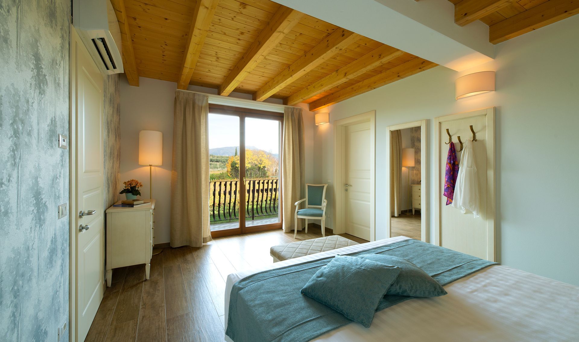 Helles Schlafzimmer mit Holzdecke, großem Fenster, Bett und Sonnenlicht mit Blick auf einen Balkon