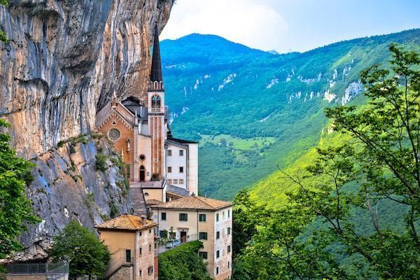 Monastero a picco su una rupe che domina una lussureggiante valle verde con le montagne sullo sfondo.