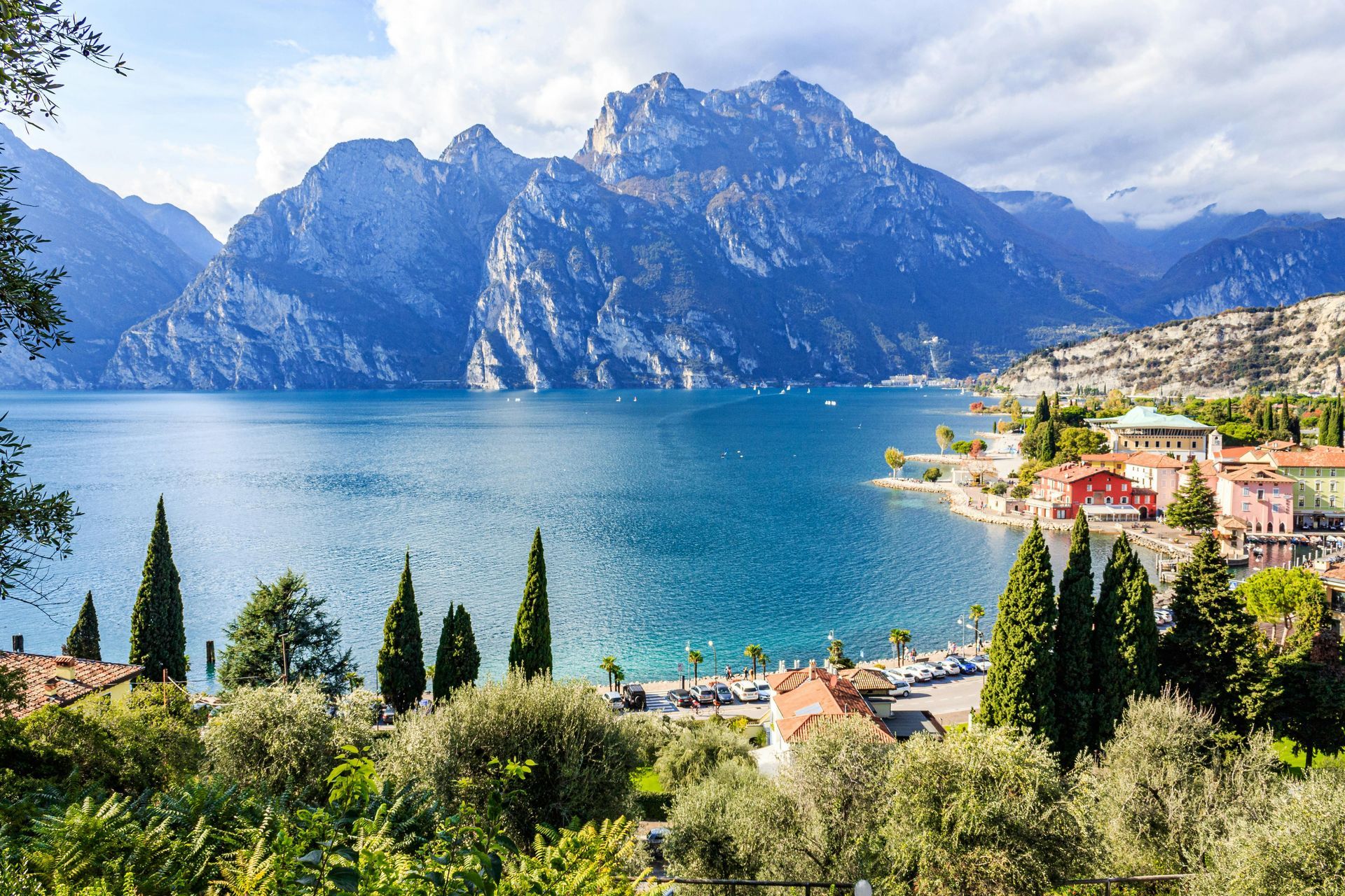 Cittadina lacustre con acque azzurre, montagne ed edifici colorati sotto un cielo limpido