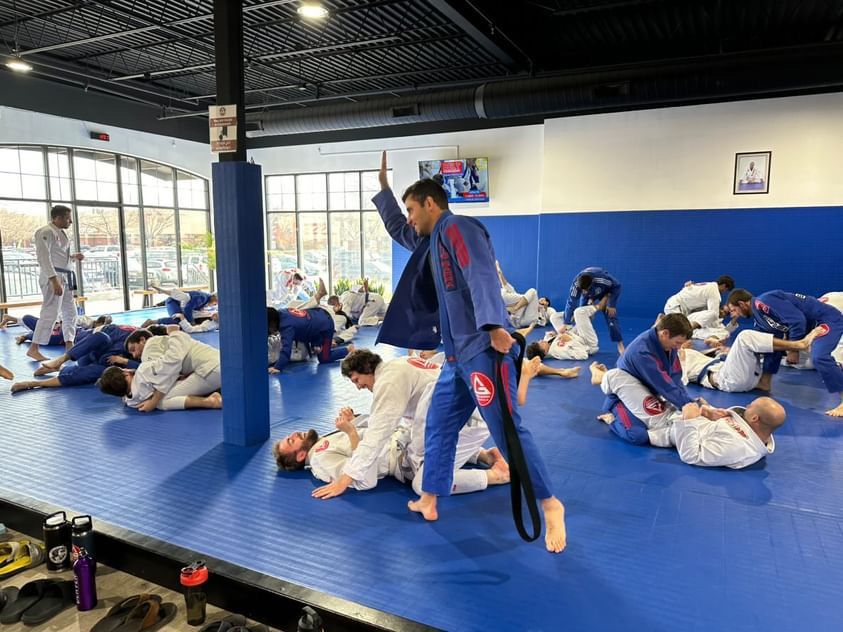 A group of people are practicing jiu jitsu in a gym.