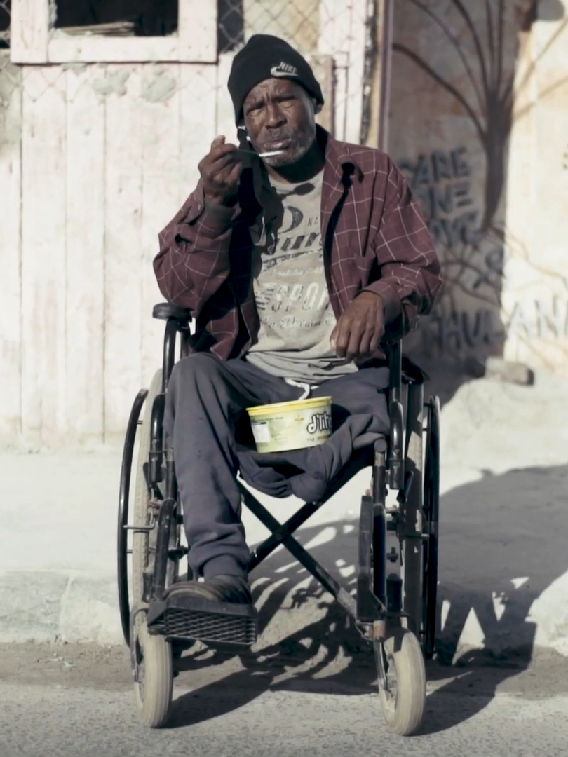 A man in a wheelchair is eating something with a spoon