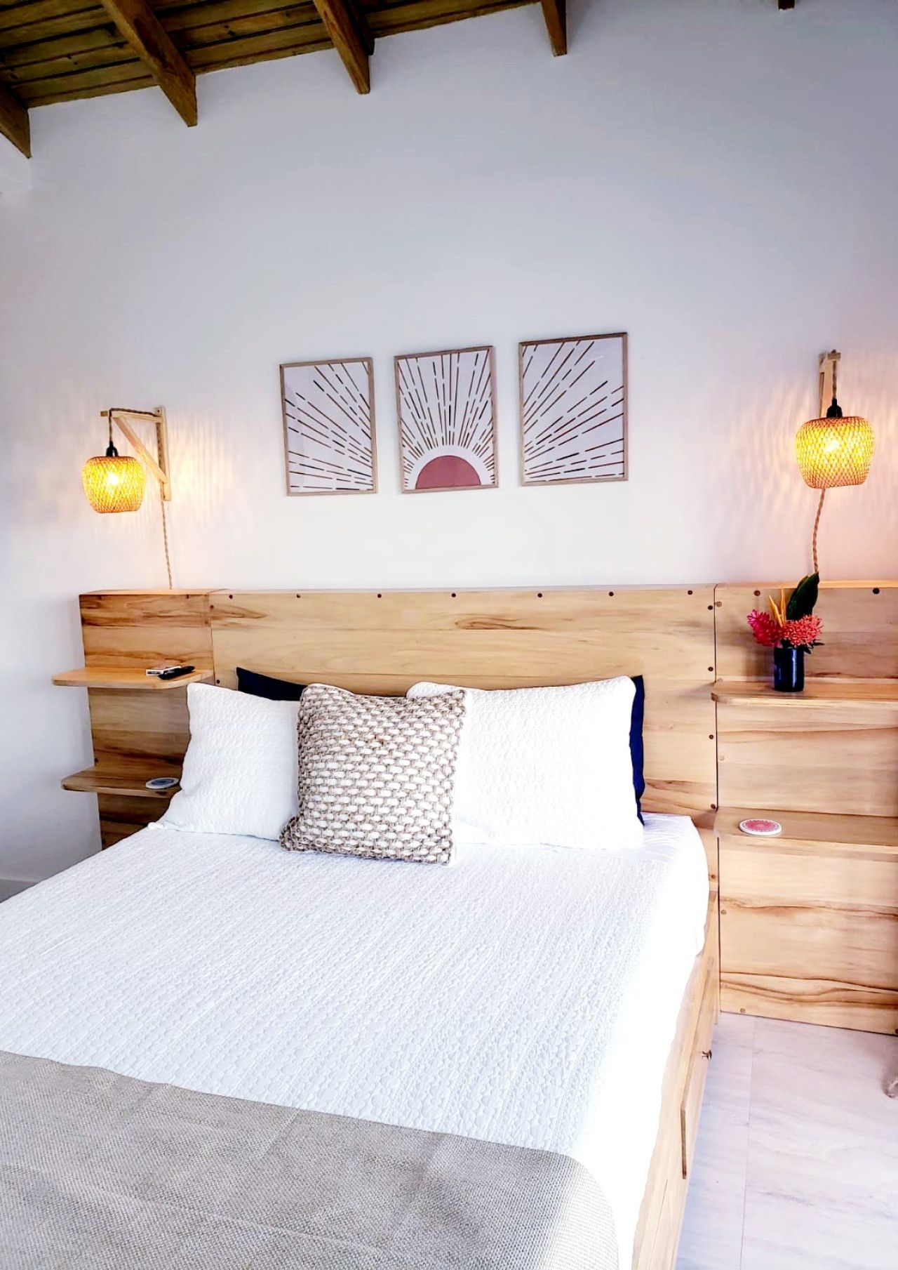 Bedroom with wooden headboard, bed, nightstands, and artwork. Soft lighting.