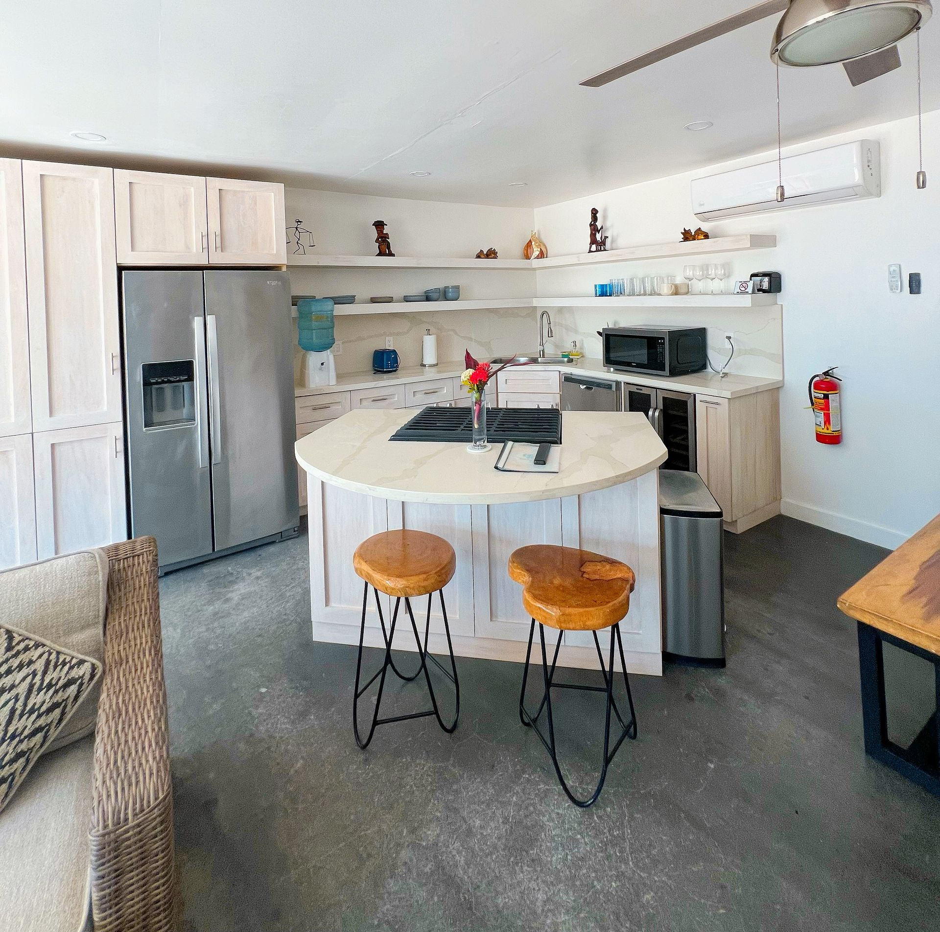 Kitchen with island, stainless steel fridge, cabinets, stools, and microwave.