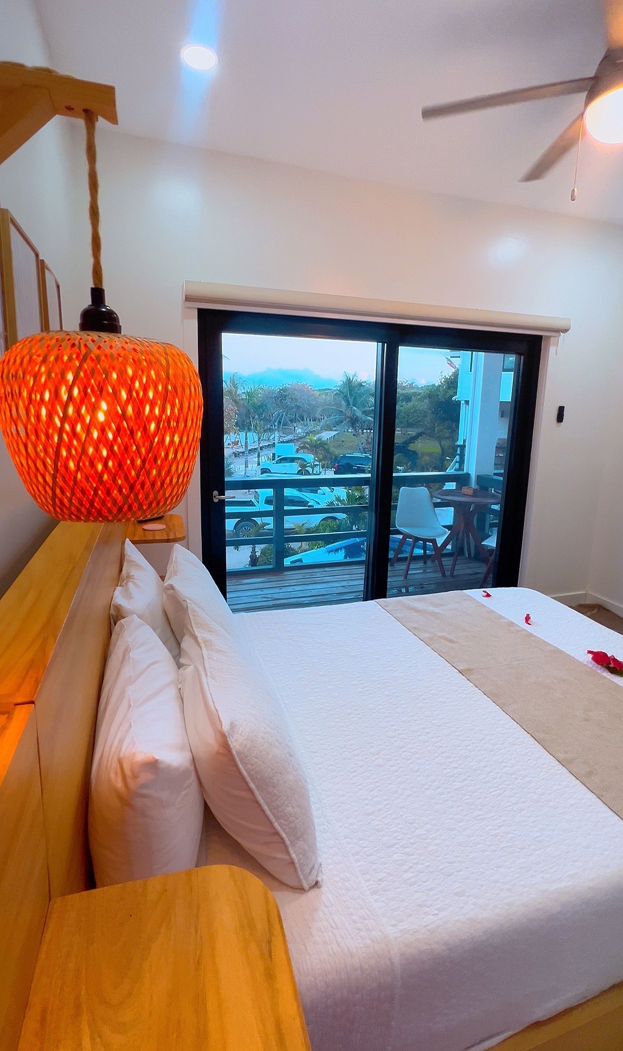 Bedroom with a large bed, a window with an outdoor view, and a hanging orange light.