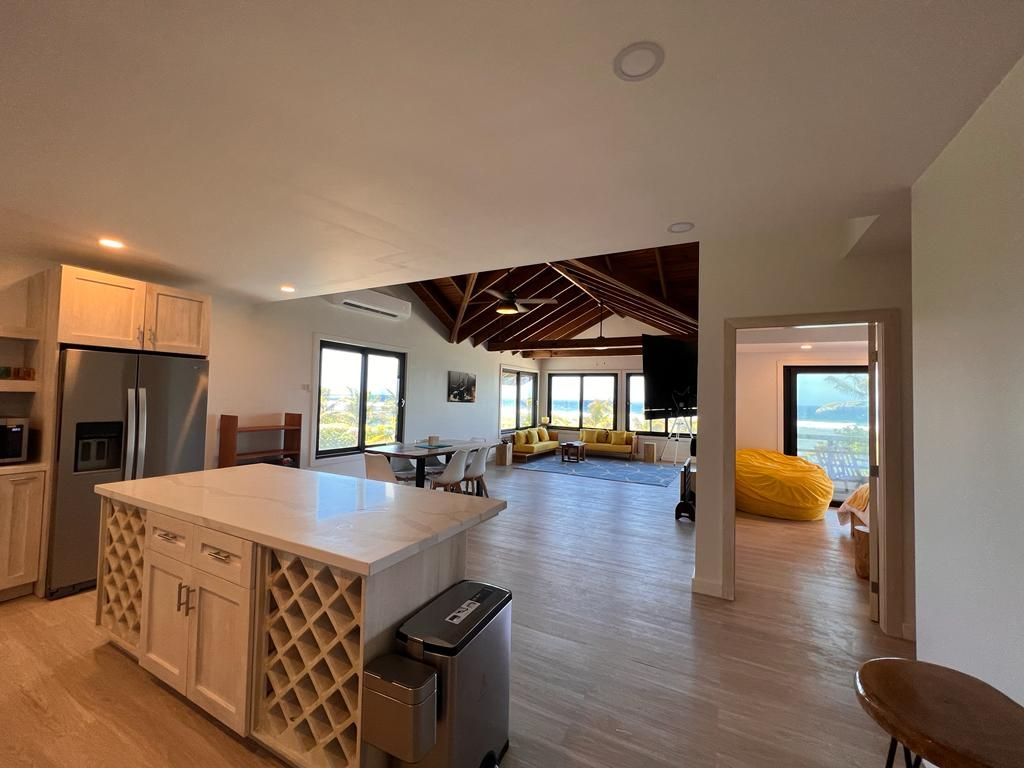 Open-concept kitchen with island and wine rack, leading to living area with water view through sliding doors.