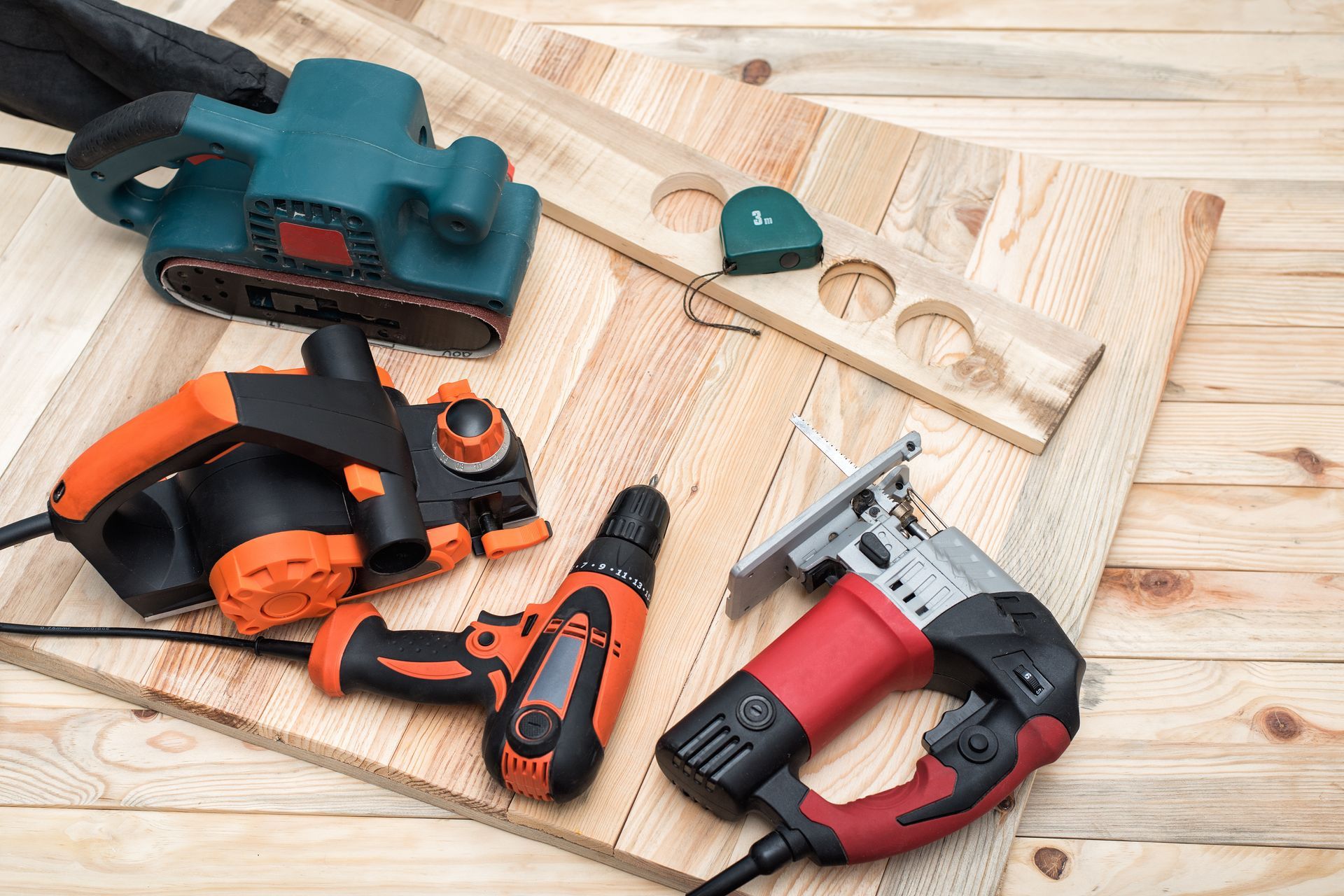 Assorted power tools and measuring equipment arranged on a wooden work surface.