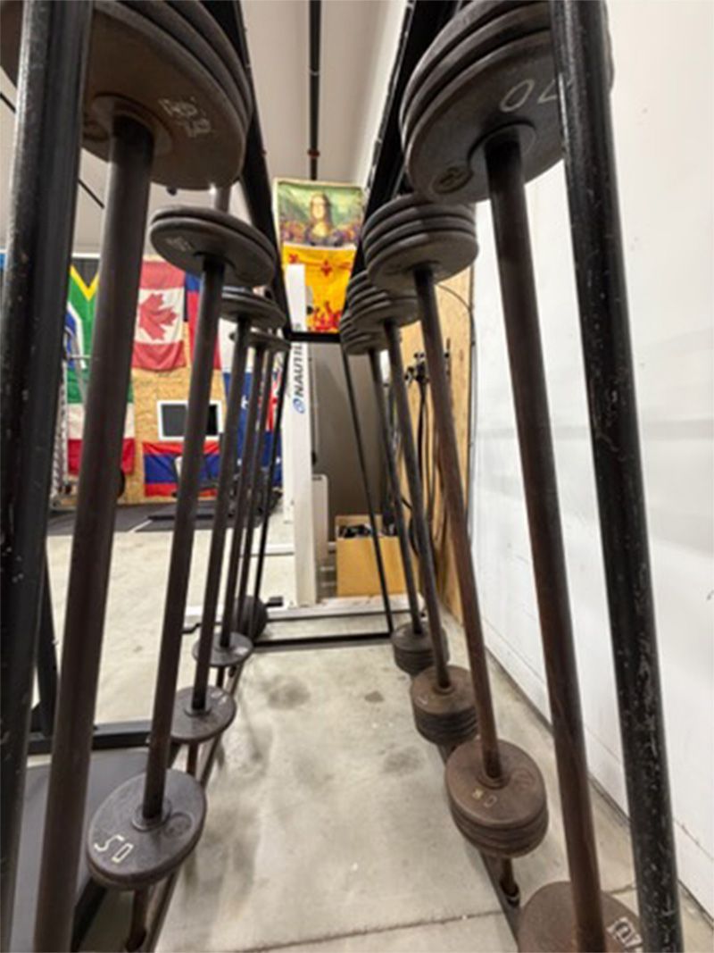 Rows of black bar stools lined up on a polished floor in a narrow restaurant aisle.