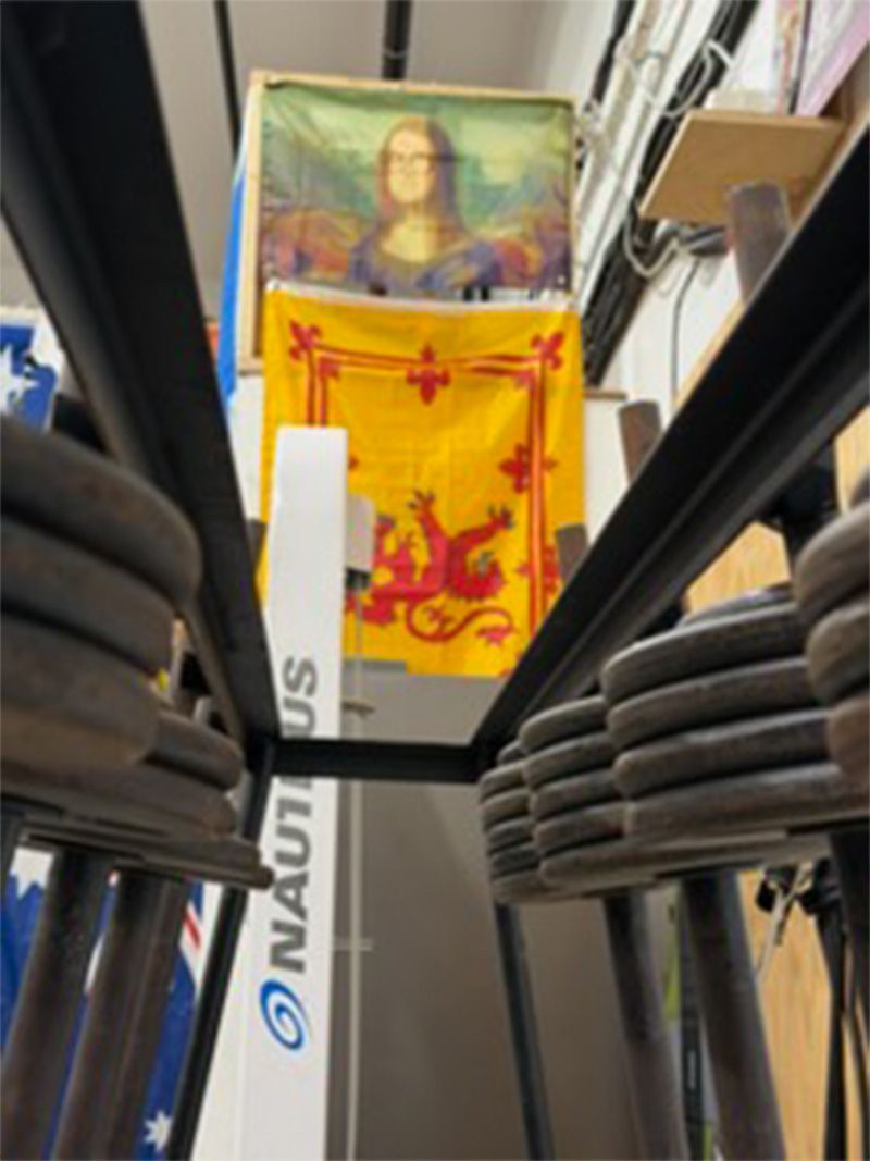 Yellow and red flag hanging on a vertical pole, viewed between rows of black seats in a bus or train aisle
