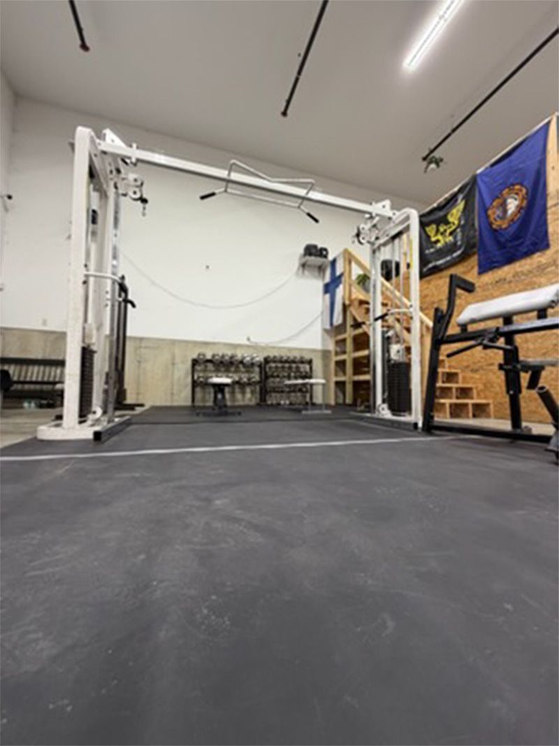 Empty gym with a squat rack, bench, and flags on the wall