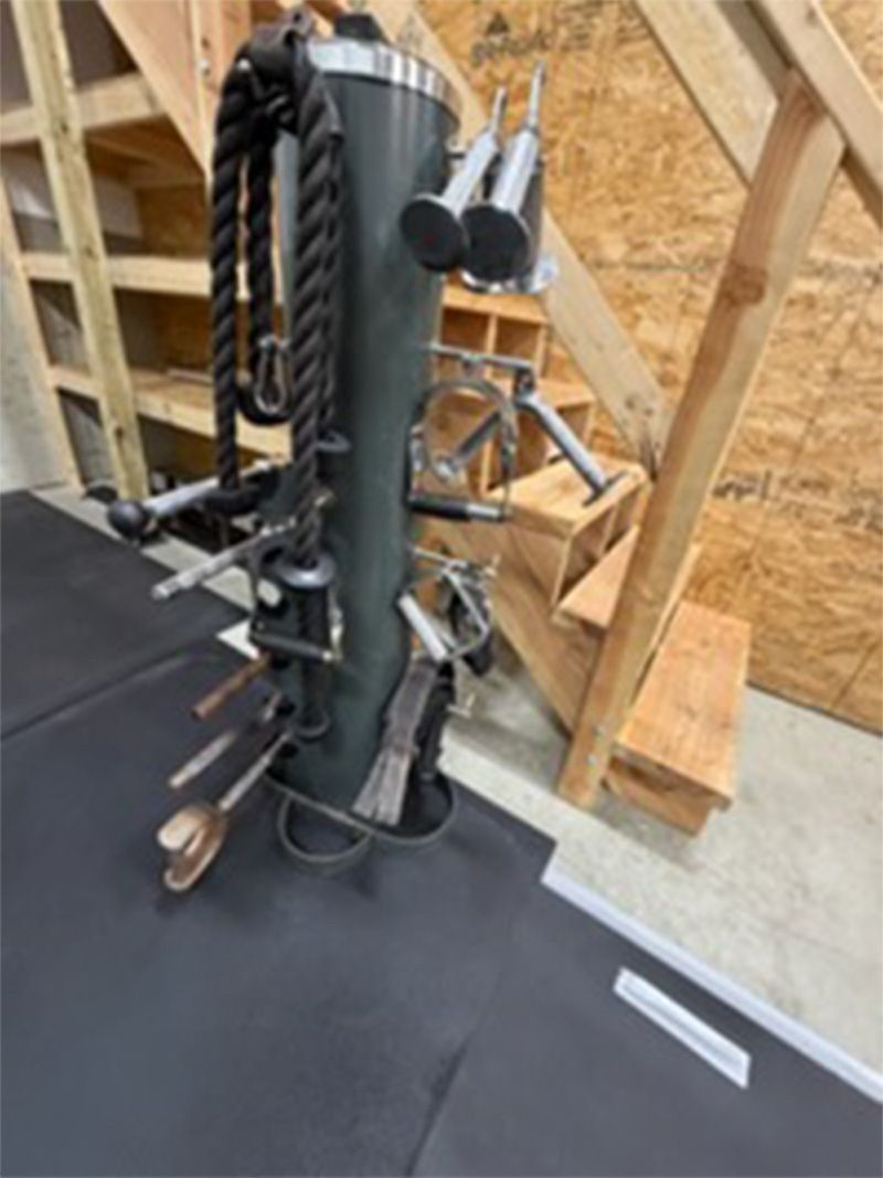 Coiled ropes and metal pipes stored on a stand in an unfinished wooden attic space