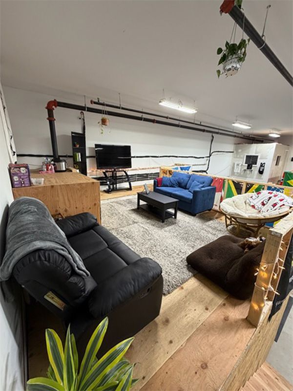 Loft living room with black and blue sofas, coffee tables, and string lights under exposed beams