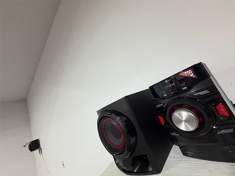 Black gaming computer with red-lit fans mounted on a wall against a white ceiling