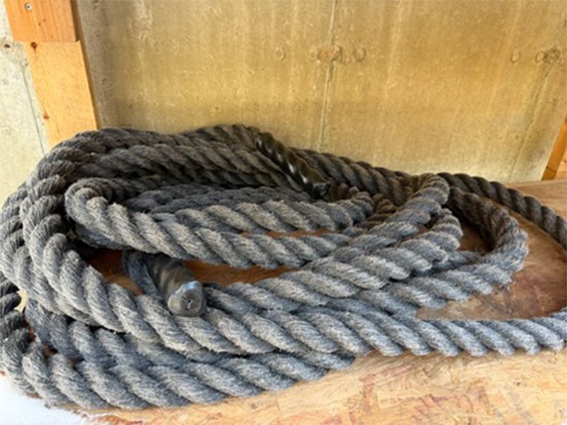 Coiled gray rope on a wooden surface against a wood-paneled background