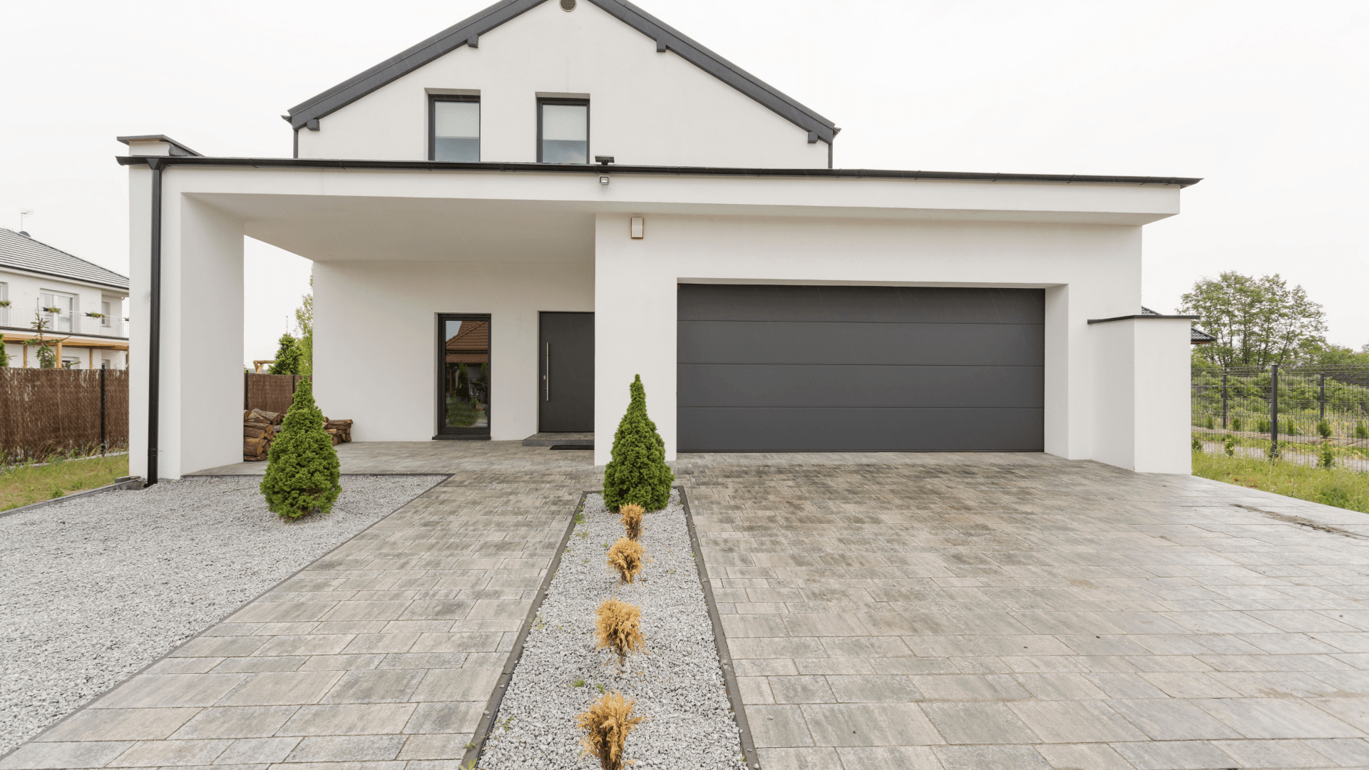Picture of a concrete slab driveway.  The concrete has stamped concrete designs on it.  It is in front of a white modern house.