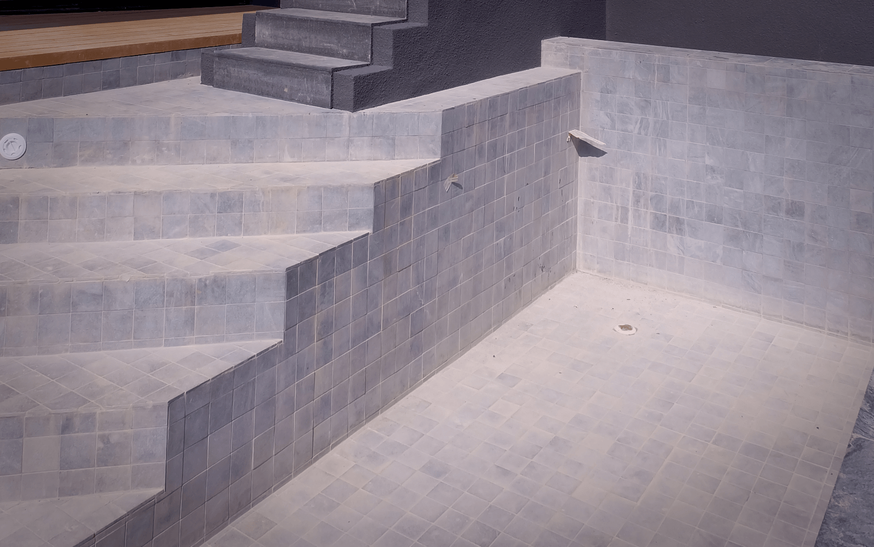 Picture of concrete steps leading from a concrete patio up to a deck.