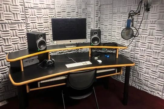 A recording studio with a computer , speakers , headphones and a microphone.