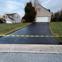 Road crew paving fresh black asphalt beside orange cones on a street
