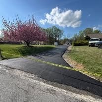 Road paving machine resurfacing a suburban street with fresh black asphalt.