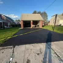Road workers in safety vests patching asphalt beside an orange dump truck on a sunny street