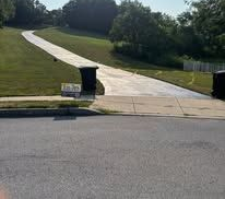 Workers in orange vests smoothing fresh black asphalt on a suburban street
