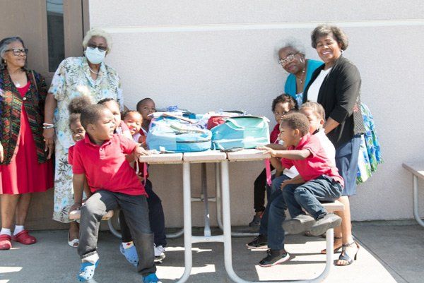 kids sitting at a table with backpacks on it