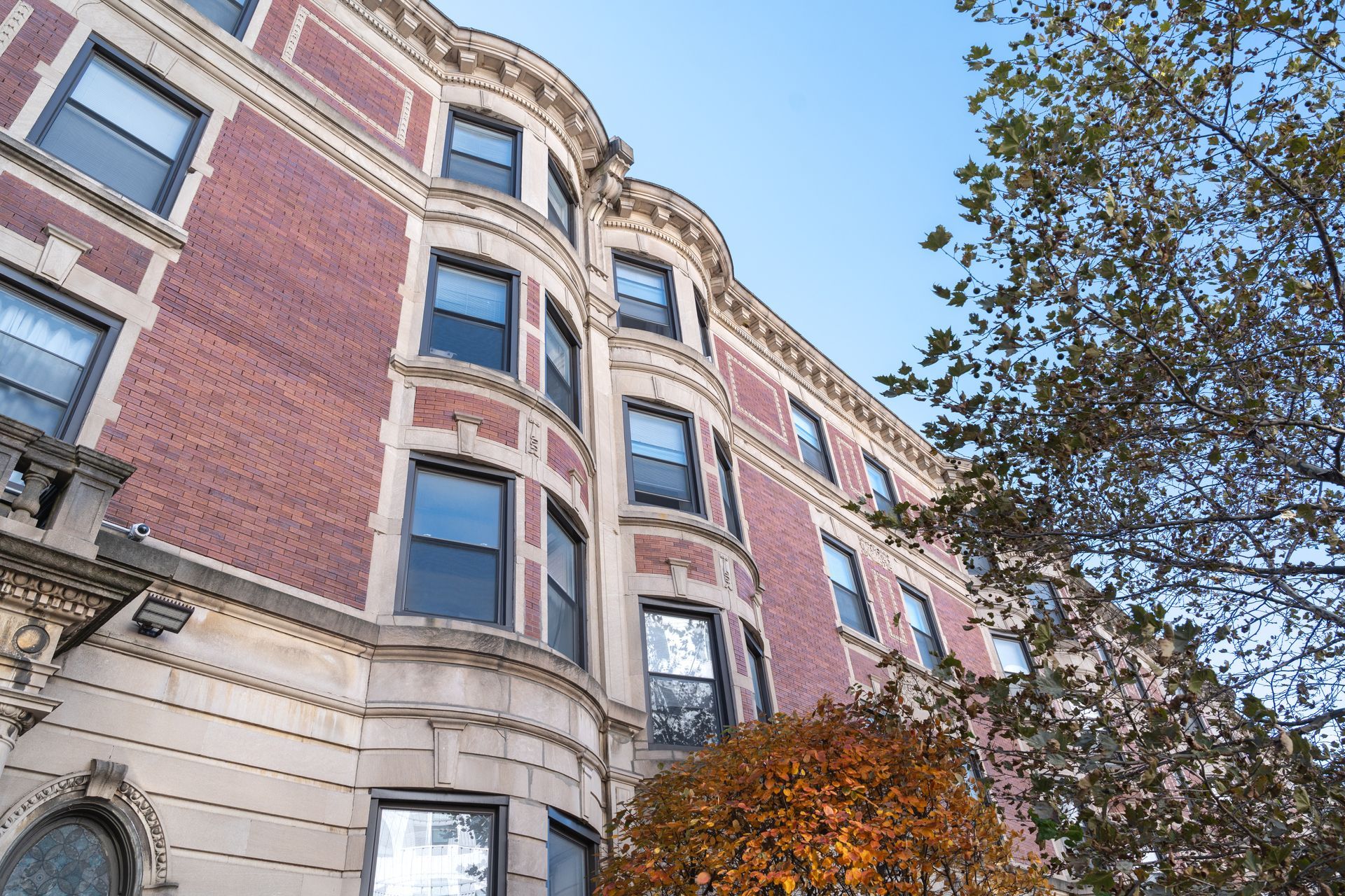 Photo of a large, multi-story building with bay windows, seen from the outside on the street level looking up